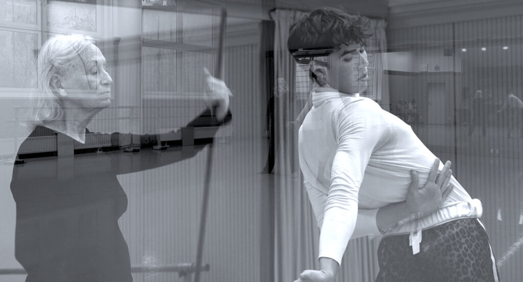 Bild in schwarzweiß. Eine ältere Frau mit schwarzer Kleidung und ein junger Mann mit weißer Kleidung bewegen sich zusammen im Raum. Das Bild ist verspiegelt.