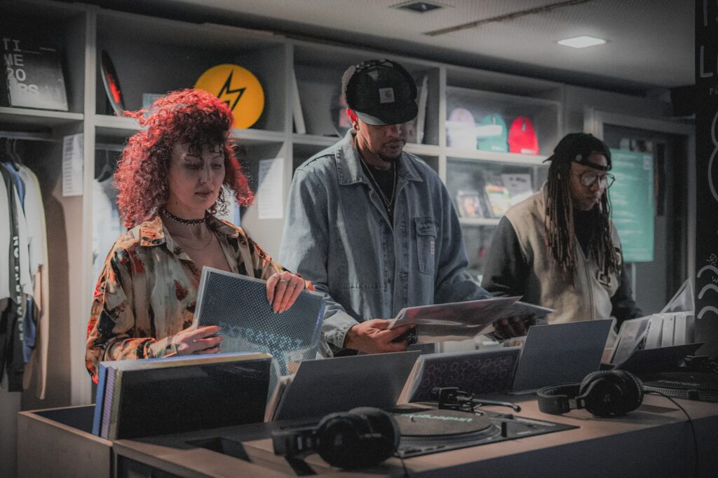 Die drei Mitglieder von HOUSEaHOLICS (Kevin, Nora und Born) schauen sich Platten in einem Plattenladen an.